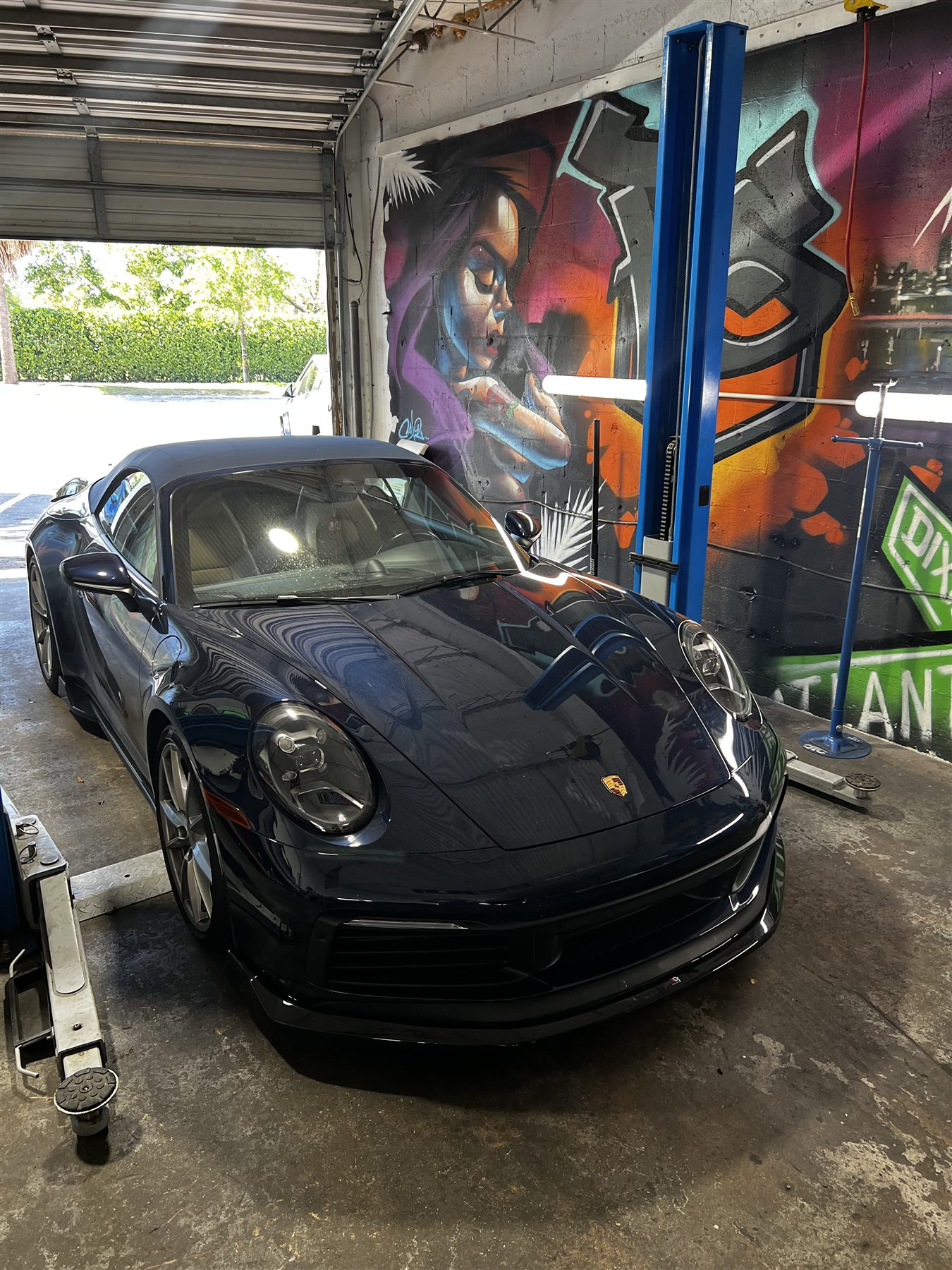 Porsche service bay with blue lift and shop murals