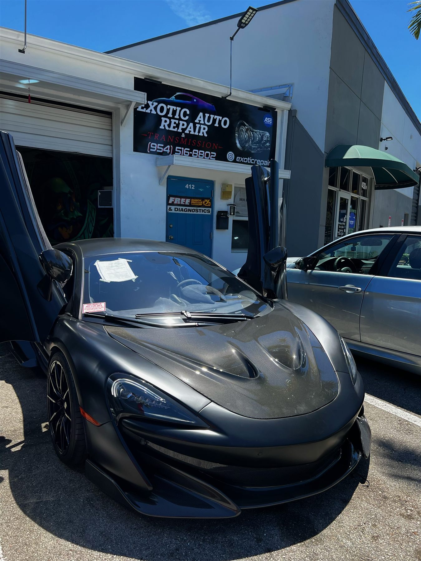 Matte black McLaren with butterfly doors outside the shop