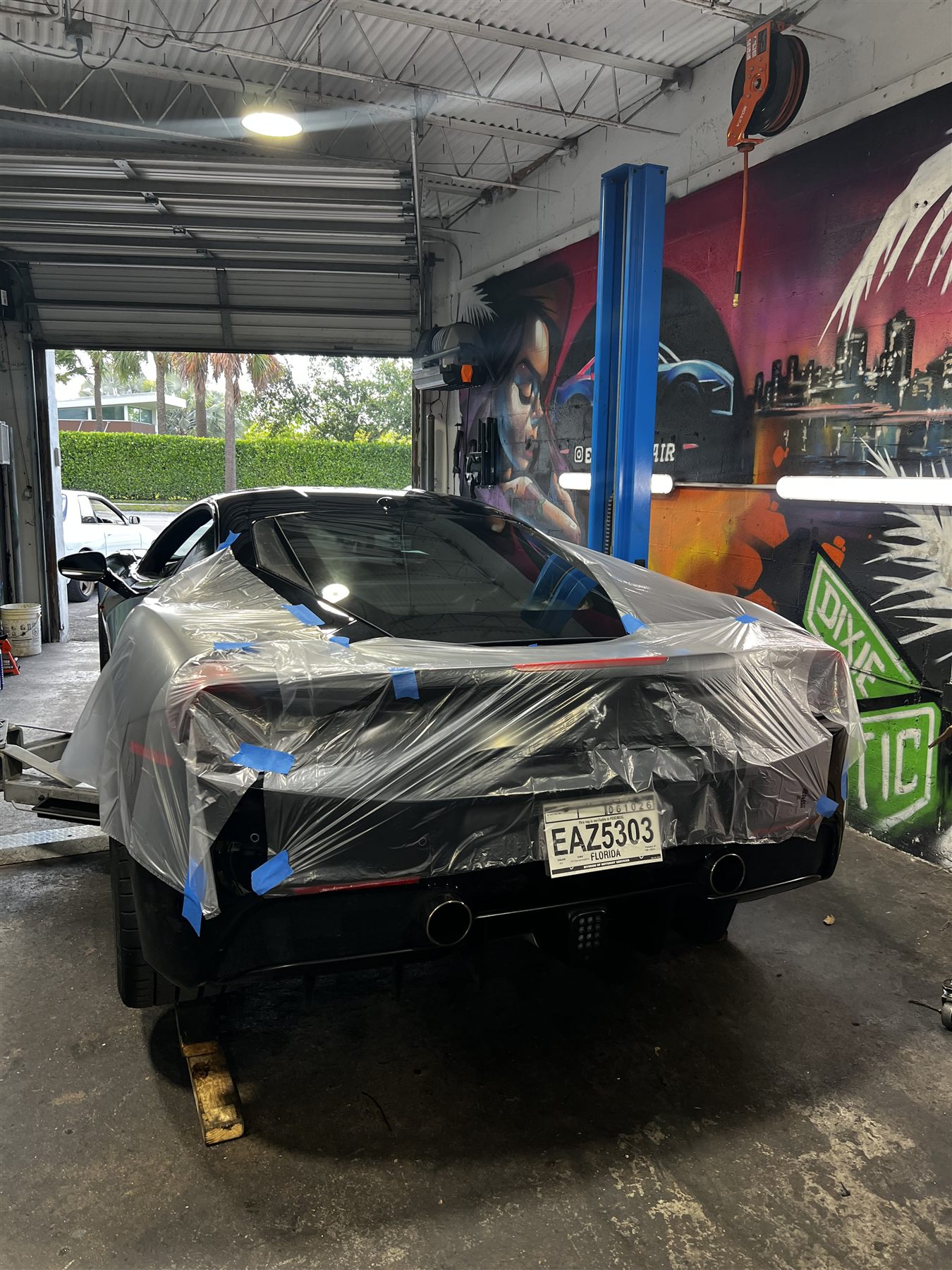 Black sports car protected for service work inside the shop